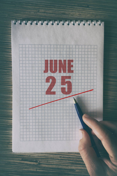25 Ιουνίου. Ημέρα 25 του μήνα, Κοντινό πλάνο του ανθρώπινου χεριού με στυλό στο σημειωματάριο με κόκκινο υπογράμμισε ημερομηνία. καλοκαίρι μήνα, ημέρα του έτους έννοια. - Φωτογραφία, εικόνα