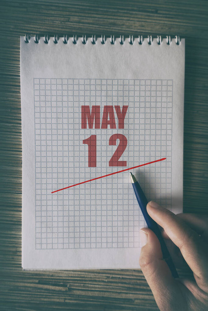 12 Μαΐου. Ημέρα 12 του μήνα, Κοντινό πλάνο του ανθρώπινου χεριού με στυλό στο σημειωματάριο με κόκκινο υπογράμμισε ημερομηνία. άνοιξη μήνα, ημέρα του έτους έννοια. - Φωτογραφία, εικόνα