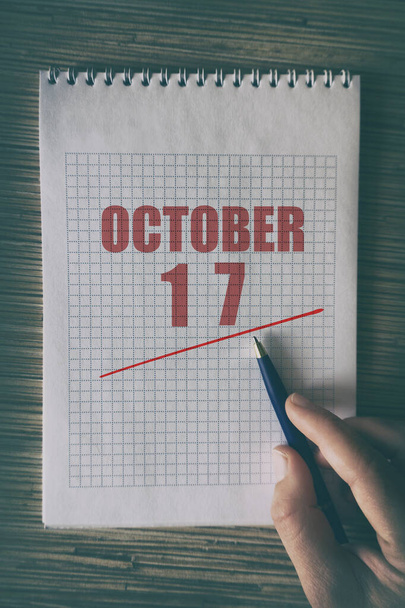 17 Οκτωβρίου. Ημέρα 17 του μήνα, Κοντινό πλάνο του ανθρώπινου χεριού με στυλό στο σημειωματάριο με κόκκινο υπογράμμισε ημερομηνία. φθινόπωρο μήνα, ημέρα του έτους έννοια. - Φωτογραφία, εικόνα