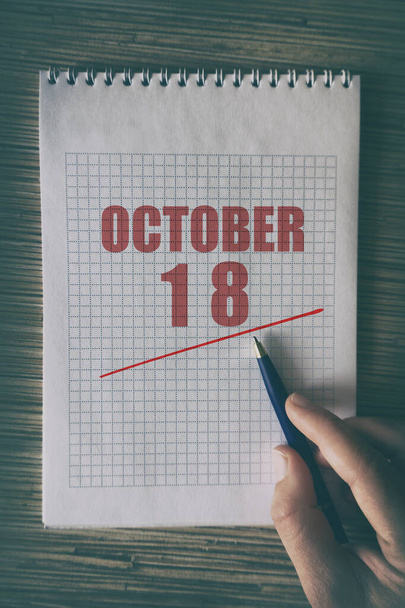 18 oktober. Dag 18 van de maand, Close-up van de menselijke hand met pen op notitieblok met rode onderstreepte datum. herfstmaand, dag van het jaar concept. - Foto, afbeelding