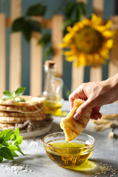 Olive oil in a large transparent bowl, basil, salt and tortillas with hand on a light table. The village history. The fence and the sunflower. Background image, copy space - Fotografie, Obrázek