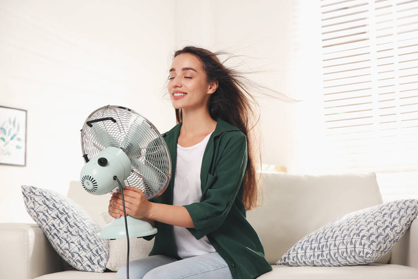 Femme avec ventilateur profitant du flux d'air à la maison. Chaleur estivale - Photo, image