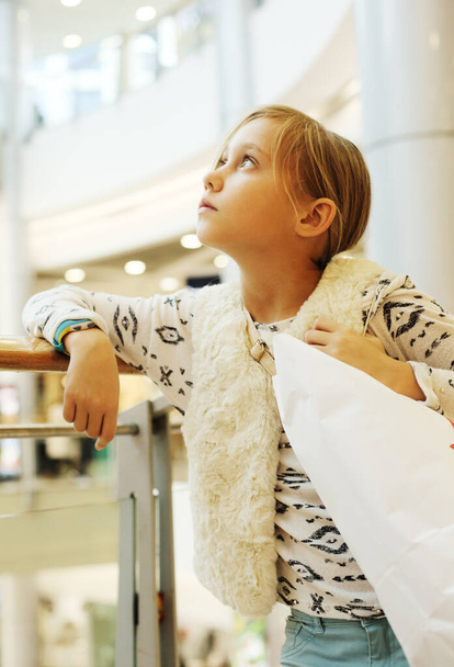 Fashion 9 years old girl with packages in shopping center - Foto, Imagem