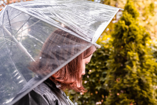Autumn. Lonely sad woman under a transparent umbrella with rain drops walking in a park, garden. Rainy day landscape. Vintage Toned - Foto, Bild