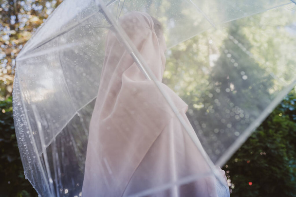 Autumn. Lonely muslim woman in a headscarf under a transparent umbrella with rain drops walking in a park, garden. Rainy day landscape. Vintage Toned - Fotó, kép