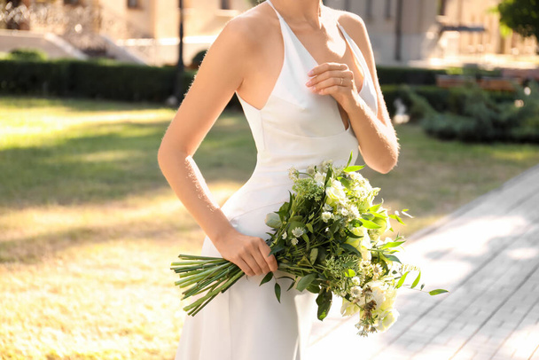 Bride in beautiful wedding dress with bouquet outdoors, closeup - Photo, image