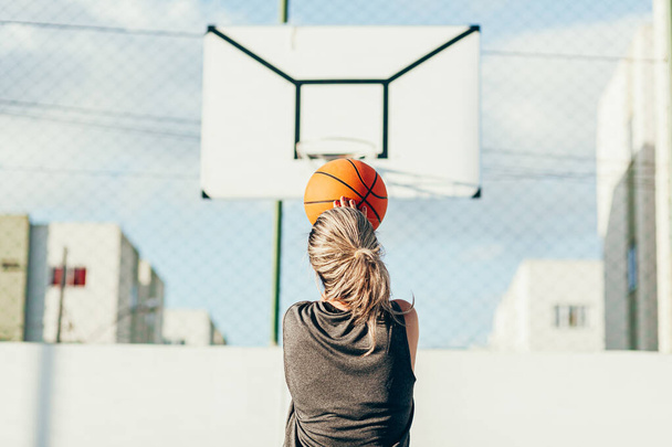 Jonge latijnse vrouw in sportkleding basketbal spelen op het buitenveld - Foto, afbeelding