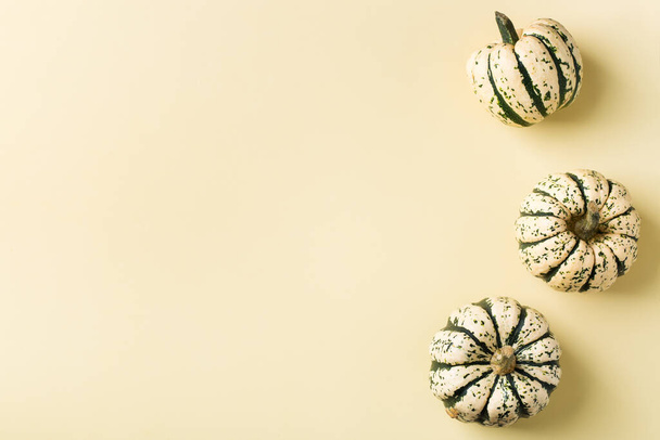 Kreatív ősz hálaadás napi kompozíció dekoratív sütőtökkel. Lapos laikus, felülnézet, másolás tér, csendélet sárga háttér üdvözlőlap - Fotó, kép