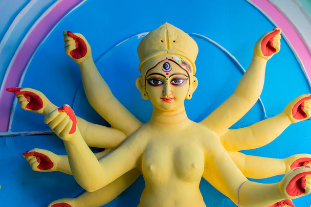 Schöne Götterfigur aus gelbem Ton, s Durga mit blauem Hintergrund in Vorbereitung auf das "Durga Puja" -Festival in Kumartuli, Kalkutta. Größtes Fest des Hinduismus. - Foto, Bild
