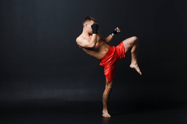 Deportista muay thai hombre boxeador postura ad rodilla patada en negro fondo - Foto, imagen