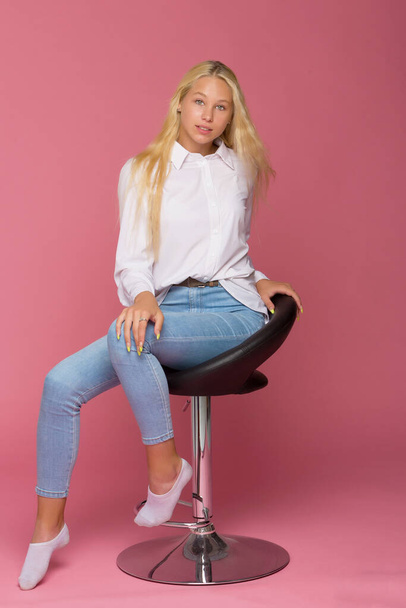 Cute Smiling Blonde Girl Sitting on High Chair in Studio - 写真・画像