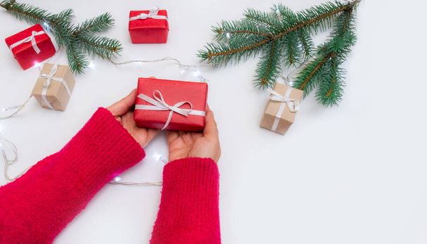 Las manos sostienen la caja de regalo sobre un fondo festivo con bolsa, cajas y árbol de Navidad - Foto, Imagen