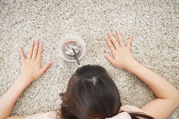 Молода азіатка лежить на килимі з випивкою
 - Фото, зображення