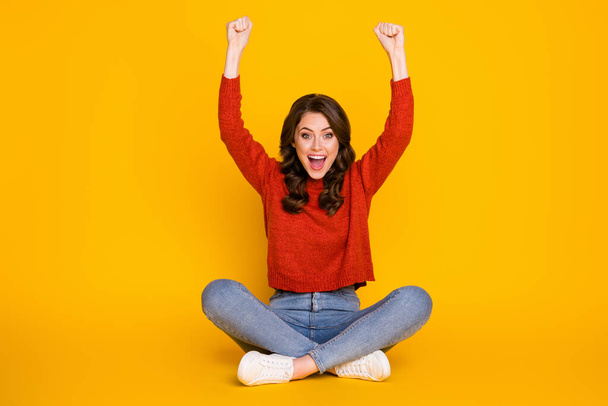 Full size photo of excited energetic girl sit floor legs crossed celebrate lottery win raise fists scream wear jeans jumper isolated bright shine color background - Zdjęcie, obraz