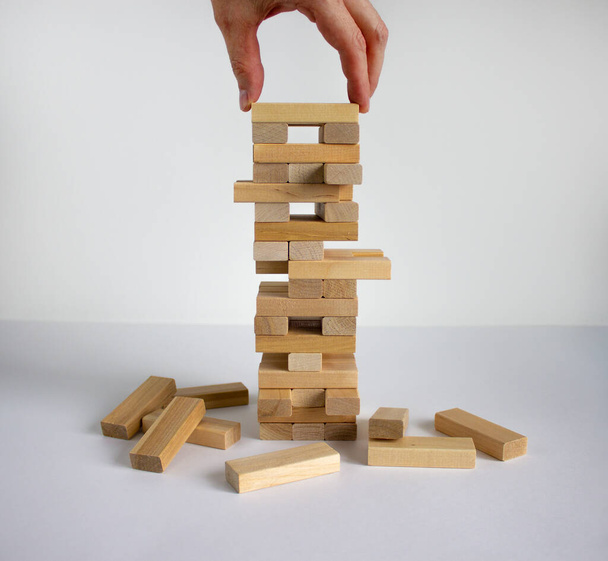 Wood block tower with architecture model. Concept Risk of management and strategy plan, growth business success process and team work. Male hand. Beautiful white background, copy space. - Фото, изображение