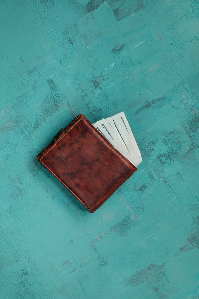 brown men's wallet with dollars on a green concrete background. - Photo, Image