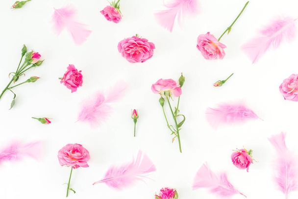 Motif floral de roses roses fleurs et plumes sur fond blanc. Couché plat, vue du dessus. - Photo, image