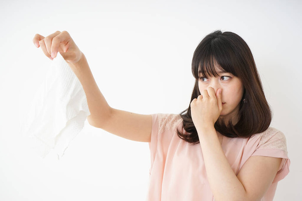 Νεαρή γυναίκα μυρίζει βρωμερά πλυντήρια - Φωτογραφία, εικόνα