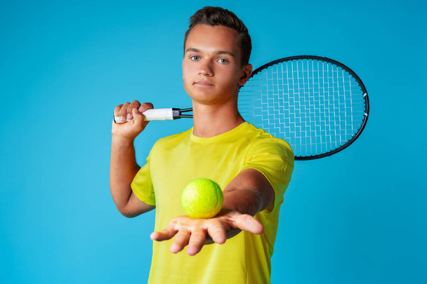 Young man tennis player in sportswear posing against blue background - Φωτογραφία, εικόνα