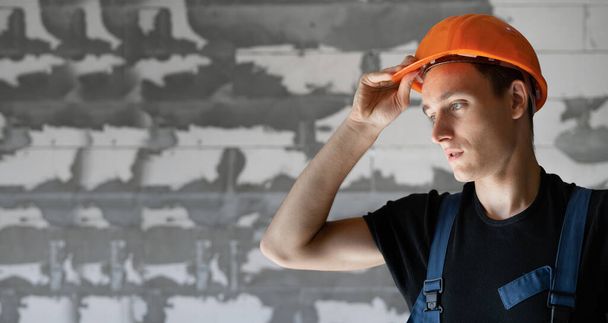 Erkek müteahhit, iş kıyafetleri ve turuncu bir şapka giyiyor. yakın plan portre - Fotoğraf, Görsel