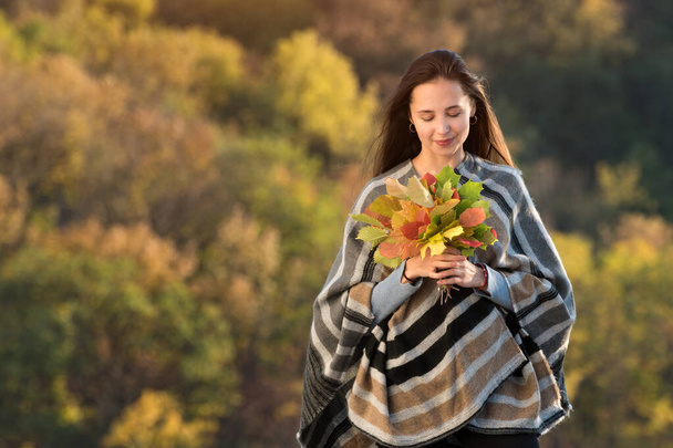 Junge Frau mit einem Strauß Herbstblätter. Naturschönheit. Angst vor alterndem Konzept. - Foto, Bild