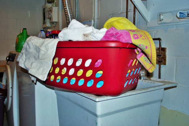 Mand vol vuile handdoeken die gewassen moeten worden in een wasruimte in de kelder - Foto, afbeelding