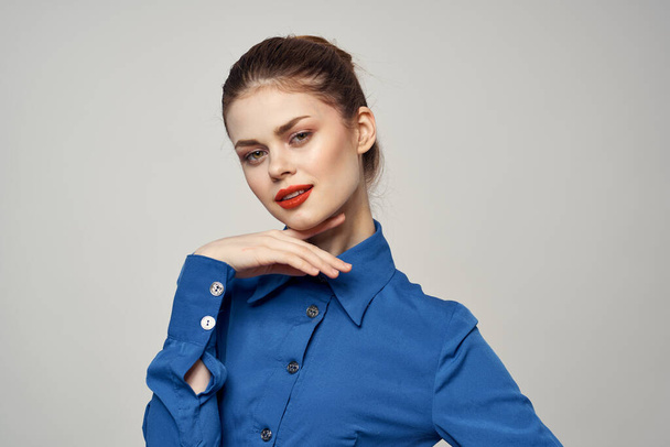 An elegant lady in a blue shirt is gesturing with her hands on a light background and a copy space close-up portrait - Foto, Imagen