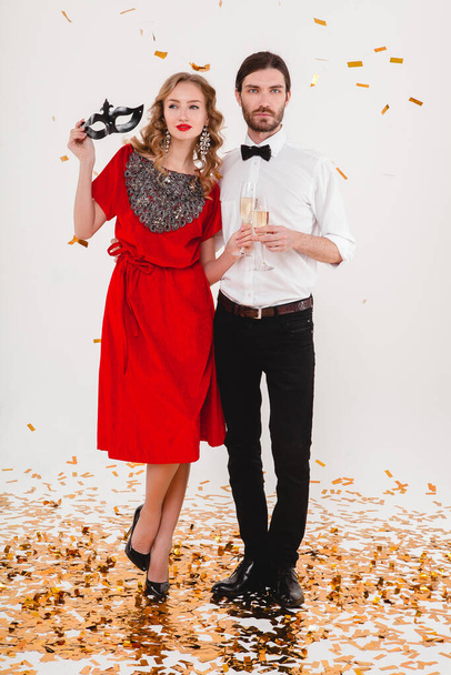 jeune couple élégant amoureux célébrant la fête du Nouvel An, portant une robe rouge, masque, tenant des verres de champagne, mode de style de luxe - Photo, image