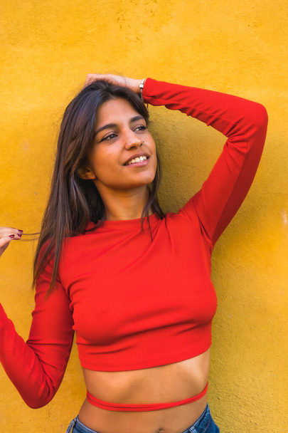 Lifestyle, young Caucasian woman in a red long-sleeved shirt. On a yellow wall background - Foto, Bild