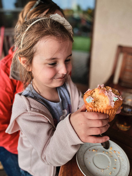 Girl enjoying eating sweet tasty cupcake that you she made herself at home - Photo, Image