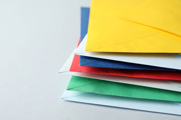 Stack of colorful paper envelopes on light background, closeup - Foto, afbeelding