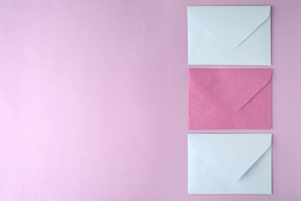 Sobres de papel de colores sobre fondo rosa, plano. Espacio para texto - Foto, Imagen