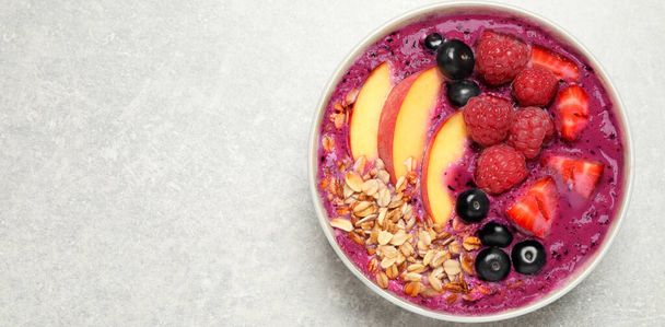 Healthy breakfast with delicious acai smoothie in bowl on light grey table, top view. Space for text - Photo, Image