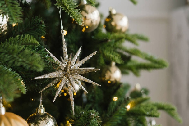 Χριστουγεννιάτικο παιχνίδι αστέρι και μπάλες κρέμονται στο δέντρο, διακοσμημένα με φώτα - Φωτογραφία, εικόνα