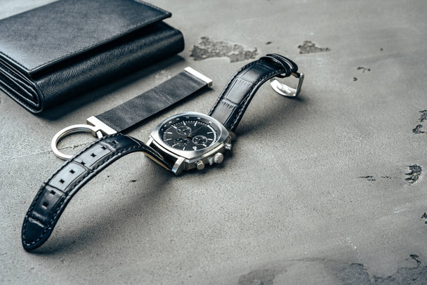 Male watch and leather wallet on dark grey surface - Foto, Imagen