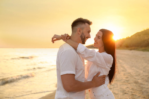 Happy young couple on beach at sunset - Фото, зображення