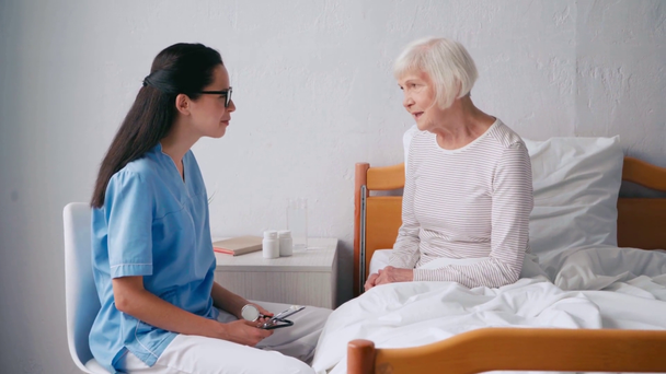 Esmer doktor hastanede yaşlı bir kadınla konuşuyor. - Video, Çekim
