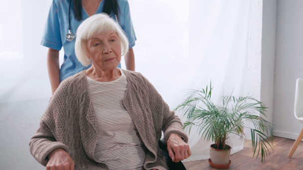 Геріатрична медсестра рухається літня жінка в інвалідному візку
  - Кадри, відео