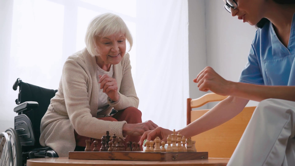 Genç hemşire yaşlı kadınla satranç oynarken hiçbir işaret göstermiyor. - Video, Çekim