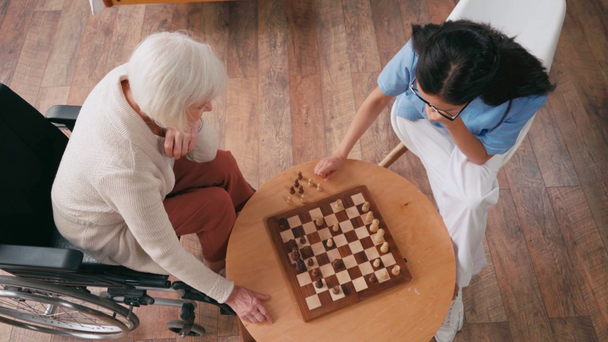 Huzurevinde satranç oynayan yaşlı kadın ve hemşire. - Video, Çekim