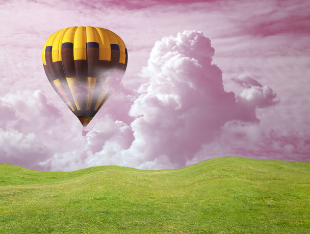 Dream world. Hot air balloon in pink cloudy sky over green meadow - Foto, Imagen