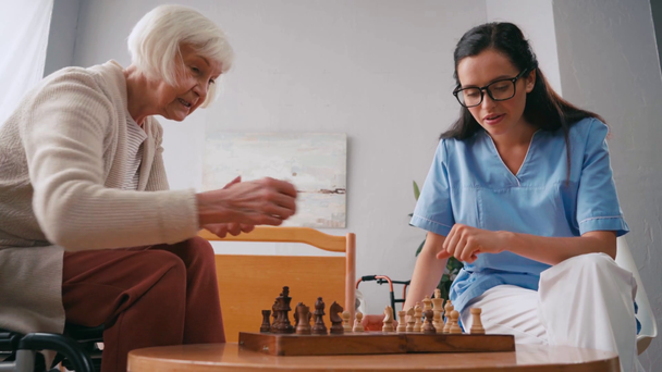 infirmière gériatrique et femme âgée parlant tout en jouant aux échecs - Séquence, vidéo
