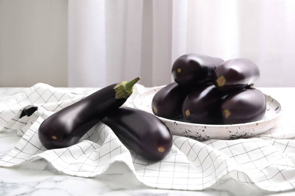 Raw ripe eggplants on white marble table - Valokuva, kuva