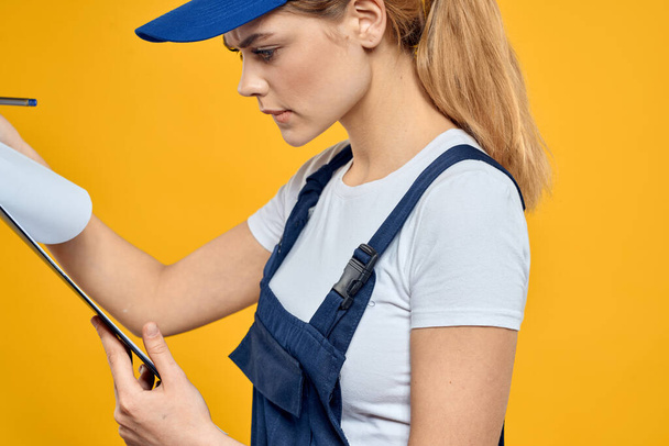 mujer en el trabajo documentos uniformes servicio de mensajería fondo amarillo - Foto, Imagen