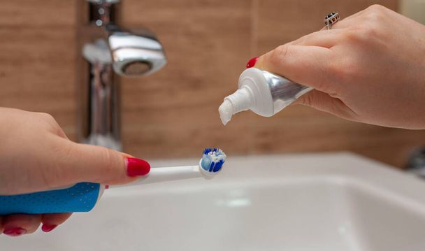 Pasta de dentes Escova de dentes Fundo desfocado Colar espremendo do tubo à escova de dentes Higiene oral. Dentes limpos. O guindaste está desfocado. Concentre-se em escova de dentes e pasta de dentes. - Foto, Imagem