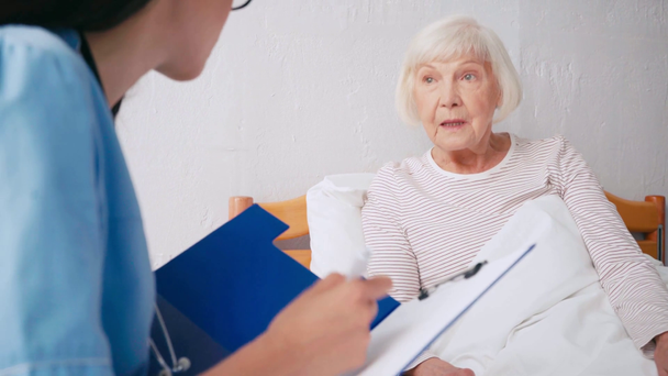 geriatra prescrição escrita, falando com a mulher idosa em fundo turvo - Filmagem, Vídeo