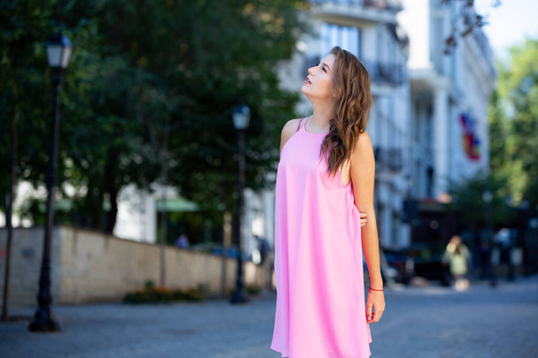 Όμορφη Ευρωπαία κοπέλα με καλοκαιρινό φόρεμα που περπατάει στο δρόμο. Σέξι νεαρή γυναίκα με κόκκινο φόρεμα. - Φωτογραφία, εικόνα