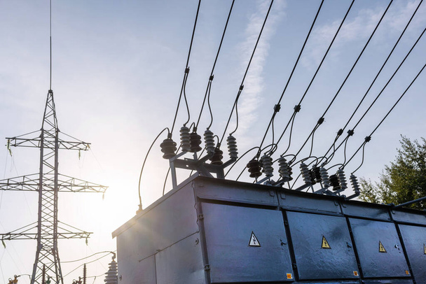 Electric power transmission lines in the evening. High voltage switchgear and equipment of power plant. - Photo, Image