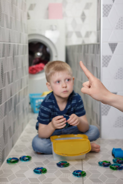 Child safety concept. Mom tells the boy not to play with the washing capsules - Photo, Image