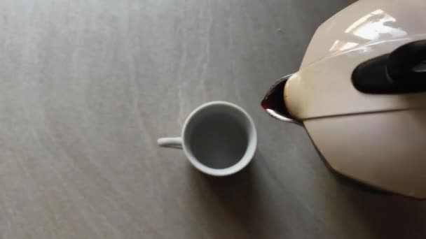 Vista dall'alto di una caffettiera moka versando caffè caldo in una tazza di ceramica bianca. Un espresso italiano. Pausa caffè - Filmati, video